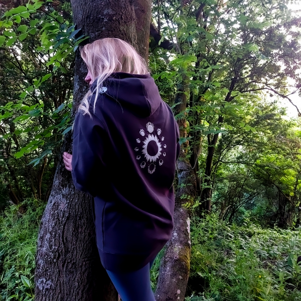 Dusk to Dawn hoodie modelled by a blonde haired woman leaning on a tree